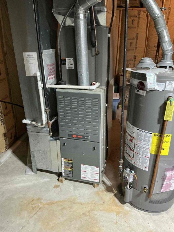 Performed comprehensive inspection of 21-year-old Trane furnace system in residential basement mechanical room. Evaluated existing ductwork connections, supply plenum, and exhaust venting. Provided replacement estimate for aging unit, documenting current installation configuration alongside adjacent water heater to ensure proper system compatibility for potential upgrade.