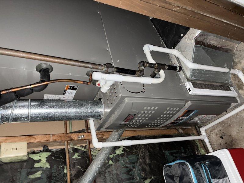 Performed scheduled maintenance service on 2-year-old central air conditioning system. Inspected furnace installation in basement, noting proper mounting on wooden platform with connected PVC condensate drain system and copper refrigerant lines. Examined air filter, which showed significant dust accumulation requiring replacement to maintain system efficiency and proper airflow.