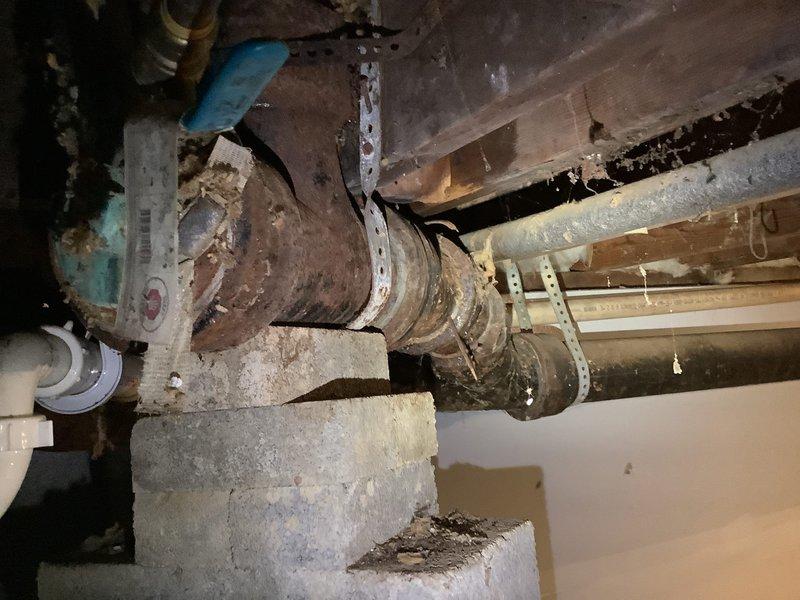Successfully replaced severely corroded 4" cast iron waste pipe system that was showing extensive deterioration. Cut out damaged sections beyond vent tie-ins, rebuilt with new PVC piping to properly service the bathroom group (lavatory, shower, and toilet). Installed new 4" PVC flange with additional wood reinforcement to create secure mounting point for toilet installation.