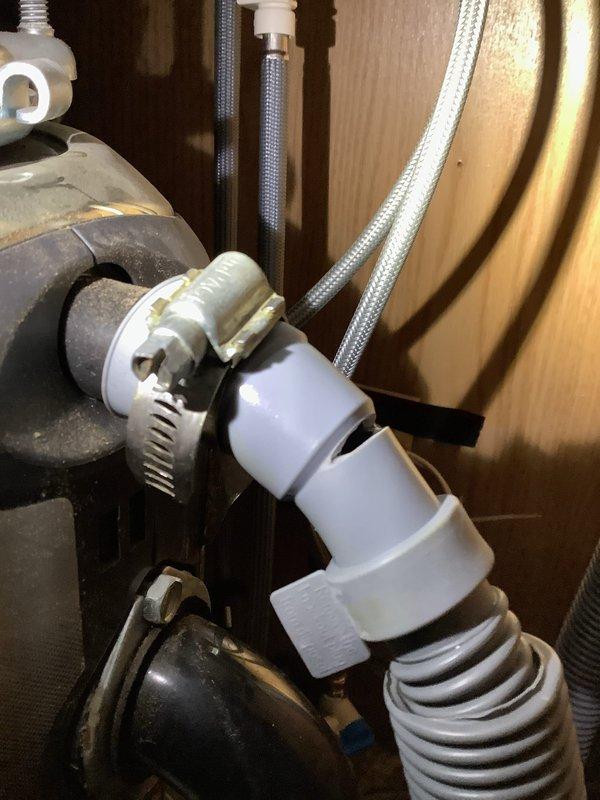 Investigated leak under 18-year-old kitchen sink with suspected dishwasher connection issue. Identified compromised drain hose fitting with inadequate sealing at connection point. Replaced damaged drain hose assembly and secured with proper metal hose clamp to prevent future leakage; also noted A.O. Smith Signature 100 water heater (MVP: 2025) functioning normally during system inspection.