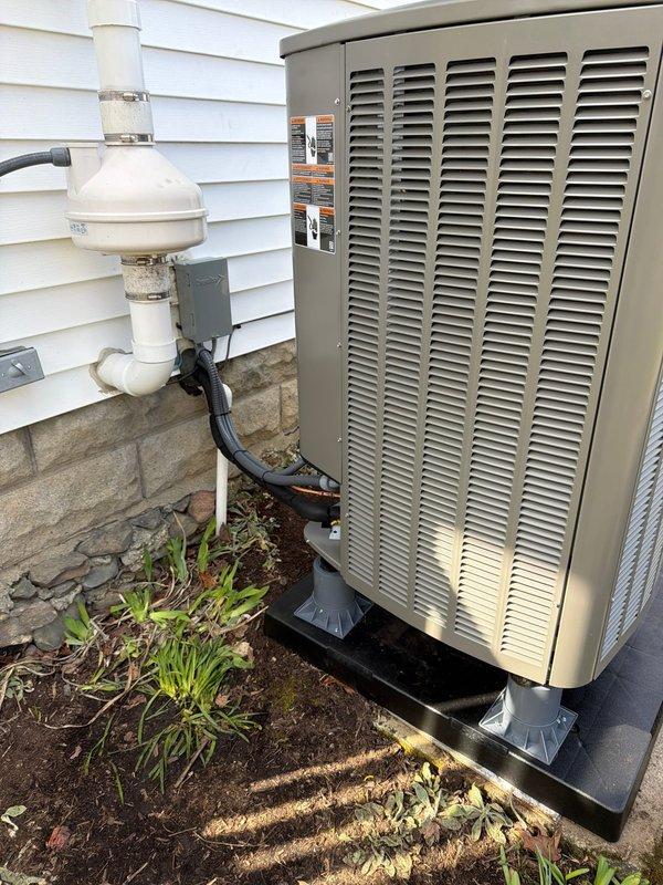 Completed installation of new Lennox dual-fuel HVAC system consisting of an oil furnace and heat pump. System includes proper condensate drainage with PVC piping and trap assembly. Unit was mounted on a stable black pad with appropriate clearances, and all refrigerant lines and electrical connections were professionally secured to the exterior of the home.