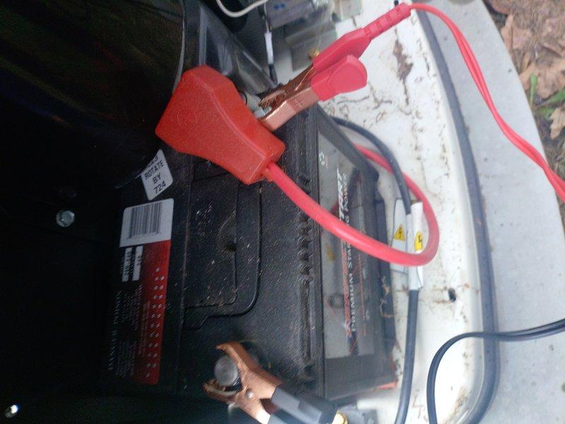 Performed scheduled maintenance on outdoor generator unit including battery terminal inspection and cleaning. Checked all electrical connections and verified proper charging system operation. Unit was successfully tested with green indicator light confirming normal operation status.