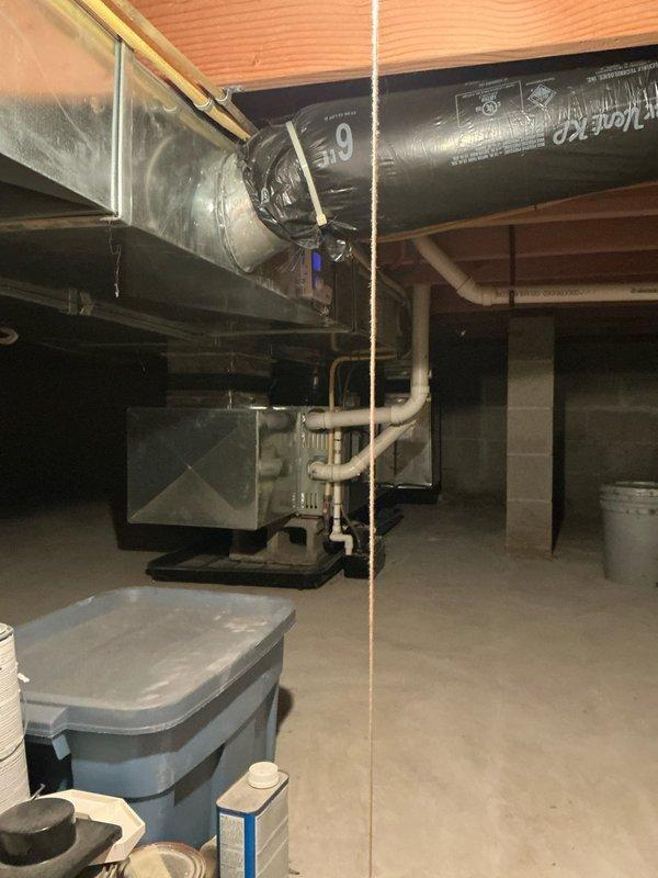 Performed diagnostic inspection of 13-year-old furnace located in crawl space, confirming significant cracking in the heat exchanger secondary. Visual examination revealed compromised heat exchanger integrity requiring complete system replacement rather than repair. Documented existing installation configuration including ductwork connections and drainage system for replacement planning.