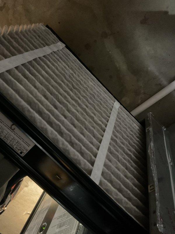 Completed recurring MVP Heating maintenance service, which included inspection and documentation of the HVAC system. Examined the pleated air filter assembly with visible securing straps and inspected the condensate drain system, noting the condition of the drain fitting and associated PVC piping with some deterioration evident. Photographic documentation was taken of key components for service records.