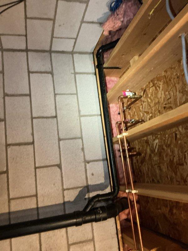 Responded to a customer service call regarding a backed-up kitchen sink in a 20-year-old residence. Upon inspection, found clogged drainage system requiring cleaning of P-trap and associated piping. Successfully cleared blockage and verified proper drainage function by testing water flow through the newly serviced system. Documented completed work with photos showing the under-sink plumbing configuration and connected drainage components.