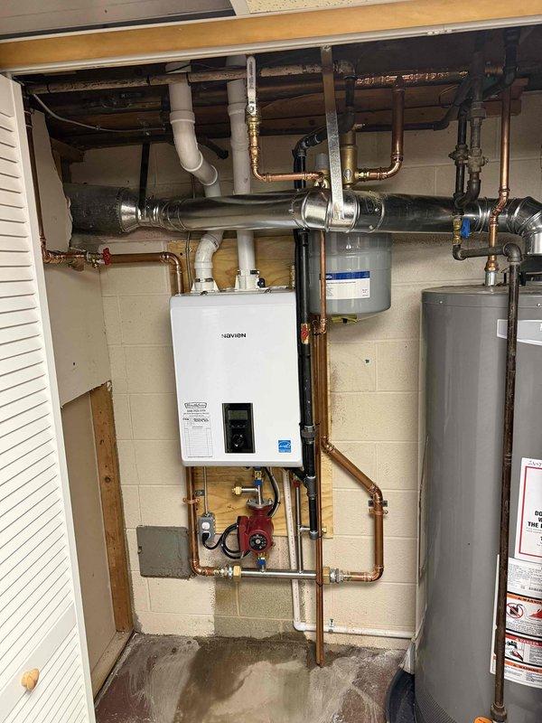 Successfully installed a high-efficiency Navien combi boiler system with three Taco zone valves, replacing the existing older blue furnace unit. System includes new copper supply lines, proper PVC venting, and an expansion tank for optimal performance. All connections were pressure tested and the system was fully commissioned with proper water flow through all zones.