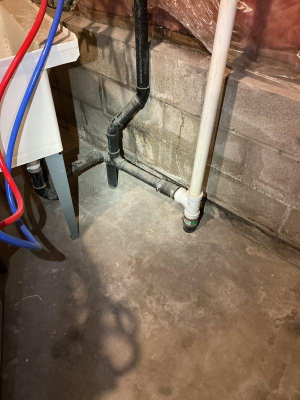 Repaired water leak in kitchen drain line where it penetrated to floor below by replacing damaged section of black PVC pipe and failed joint. Installed new properly-sealed fittings at the T-junction to eliminate ceiling leak, ensuring proper drainage from kitchen sink and dishwasher with no further water intrusion.