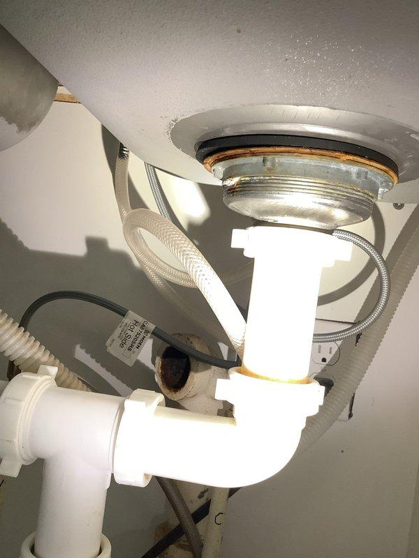 Inspected kitchen sink plumbing system exhibiting signs of corrosion and potential leaks. Replaced deteriorated P-trap assembly and associated PVC drain pipes that showed significant rust staining at connection points. Verified proper connection to existing garbage disposal unit and ensured all new components were securely installed with appropriate seals to prevent future leakage.