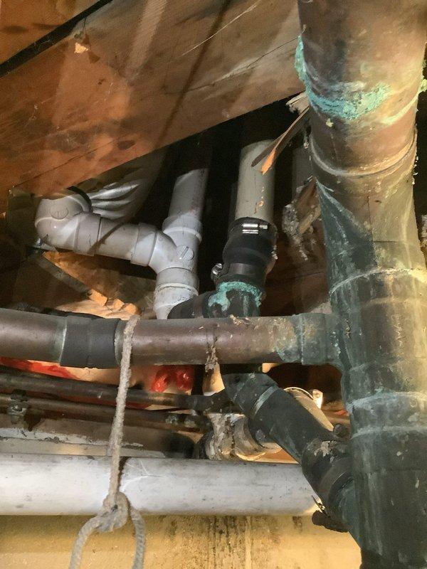 Responded to service call for clogged sink drain in a 60-year-old residence. Upon inspection, discovered significant corrosion on copper supply lines and aging drain pipes in the confined access area. Successfully cleared the blockage and verified proper drainage functionality while documenting the condition of the plumbing system, including areas with verdigris formation and deteriorating insulation that may require future attention.