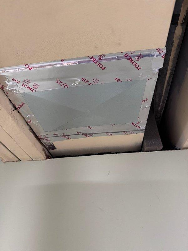 Responded to failed inspection regarding exterior seal at electrical conduit penetration to condenser unit. Documented condition with photos showing ceiling access panel installation and metal duct component within wooden enclosure. Work on hold pending manager approval.