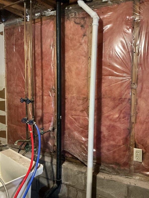 Repaired split ABS kitchen drain line by cutting pipe below floor level and installing approved transition coupling to connect ABS to PVC. Rebuilt drainage system and tied back to vertical PVC pipe with standard coupling. Replaced lower fernco with approved transition coupling on horizontal pipe to laundry tub, resolving leak issues.