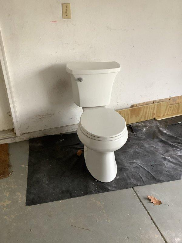 Successfully cut exposed 3" ABS line in garage and re-piped with new toilet flange for upstairs bathroom. Completed installation of white toilet on protective moisture barrier over concrete flooring, ensuring proper connection to the newly installed plumbing system.