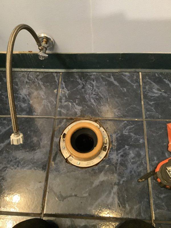 Successfully installed new American Standard Champion toilet with round bowl and comfort height. Replaced corroded drain pipe and installed new toilet flange on marble-patterned floor. Completed connection of water supply line to shut-off valve, ensuring proper function of the new fixture.