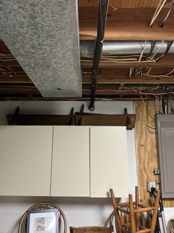 Conducted on-site assessment for furnace and air conditioning replacement. Inspected existing HVAC system located in basement utility area, including air handler unit with metal casing, associated ductwork, and drainage components. Photographed current installation to document configuration of exposed ceiling joists, electrical connections, and existing mechanical systems for proper replacement planning.