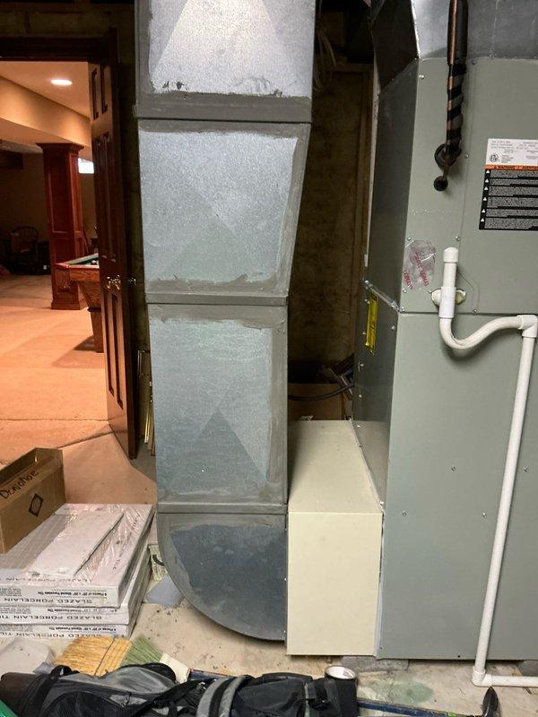 Conducted on-site assessment for furnace and air conditioning replacement. Inspected existing HVAC system located in basement utility area, including air handler unit with metal casing, associated ductwork, and drainage components. Photographed current installation to document configuration of exposed ceiling joists, electrical connections, and existing mechanical systems for proper replacement planning.