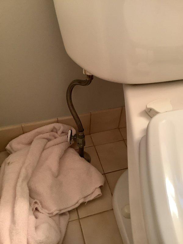 # Plumbing Service Report

## Service Summary
Responded to toilet repair request at 32-year-old residential property. Diagnosed and addressed internal tank component deterioration and mineral buildup affecting flush performance.

## Work Performed

Upon arrival, conducted visual inspection of toilet fixture and internal tank components. Removed tank lid to assess flush mechanism condition. Found significant mineral deposits and rust-colored sediment accumulated on tank floor, indicating corrosion of metal components and water quality issues. Water in tank exhibited brownish discoloration consistent with iron content or deteriorating internal hardware.

Inspected flush valve assembly with float ball and chain mechanism, noting age-related wear on black plastic components. Examined fill valve and overflow tube assembly for proper operation. Identified corroded metal hardware within tank requiring attention to prevent future leaks and ensure reliable flushing action.

Verified water suppl