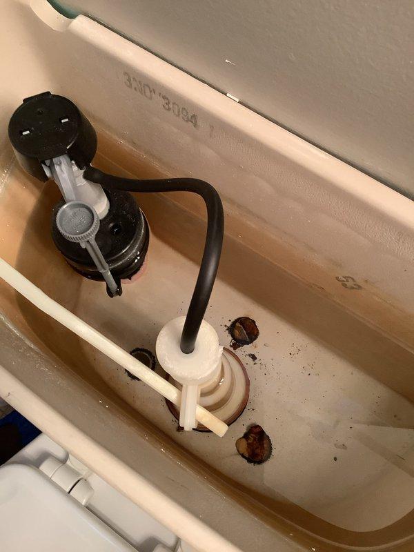 # Plumbing Service Report

## Service Summary
Responded to toilet repair request at 32-year-old residential property. Diagnosed and addressed internal tank component deterioration and mineral buildup affecting flush performance.

## Work Performed

Upon arrival, conducted visual inspection of toilet fixture and internal tank components. Removed tank lid to assess flush mechanism condition. Found significant mineral deposits and rust-colored sediment accumulated on tank floor, indicating corrosion of metal components and water quality issues. Water in tank exhibited brownish discoloration consistent with iron content or deteriorating internal hardware.

Inspected flush valve assembly with float ball and chain mechanism, noting age-related wear on black plastic components. Examined fill valve and overflow tube assembly for proper operation. Identified corroded metal hardware within tank requiring attention to prevent future leaks and ensure reliable flushing action.

Verified water suppl