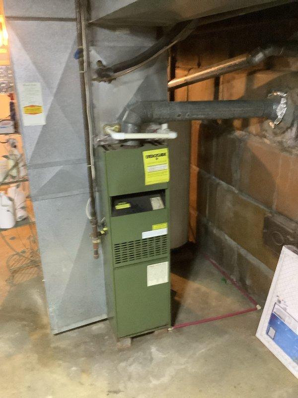 # HVAC Install - Furnace Service Report

Successfully completed installation of new green Goodman furnace unit in residential basement mechanical room. Unit was properly positioned against concrete block wall with gray insulated ductwork connected and routed through ceiling joists to existing HVAC distribution system. All manufacturer specifications verified, ventilation components secured, and system tested for proper operation. Installation completed as part of promotional program with customer collection processed accordingly.