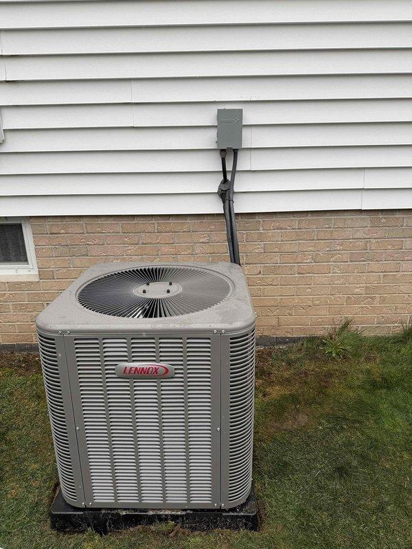 Completed outdoor unit installation for Lennox air conditioning system. Unit was properly mounted on pad with appropriate clearances, electrical disconnect and 25-amp fusing installed per manufacturer specifications, and conduit run secured to building exterior. All connections tested and system confirmed operational.