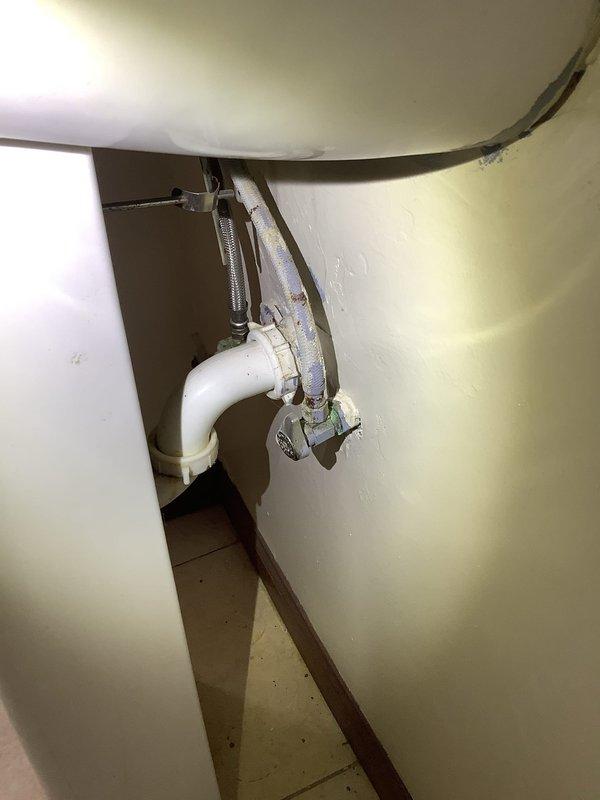 # Plumbing Service Report

Responded to service call for plumbing issue in 40-year-old residential property. Upon arrival, performed comprehensive inspection of affected plumbing systems, including under-sink connections and wall cavity piping.

Inspection revealed concerns with aging pipe infrastructure requiring access through interior wall cavity. Removed section of finished wall to expose plumbing chase containing vertical supply lines, drain stacks, and shut-off valves. Documented existing conditions showing cast iron/black steel piping, PVC drain lines, and braided stainless steel flexible supply connections beneath bathroom sink fixture.

Assessed P-trap assembly, drain connections, and water supply lines for leaks, corrosion, or damage. Verified proper operation of red and blue-handled shut-off valves controlling water supply to affected fixtures. Examined structural wooden framing for water damage or deterioration from potential previous leaks.

Completed necessary repairs to 