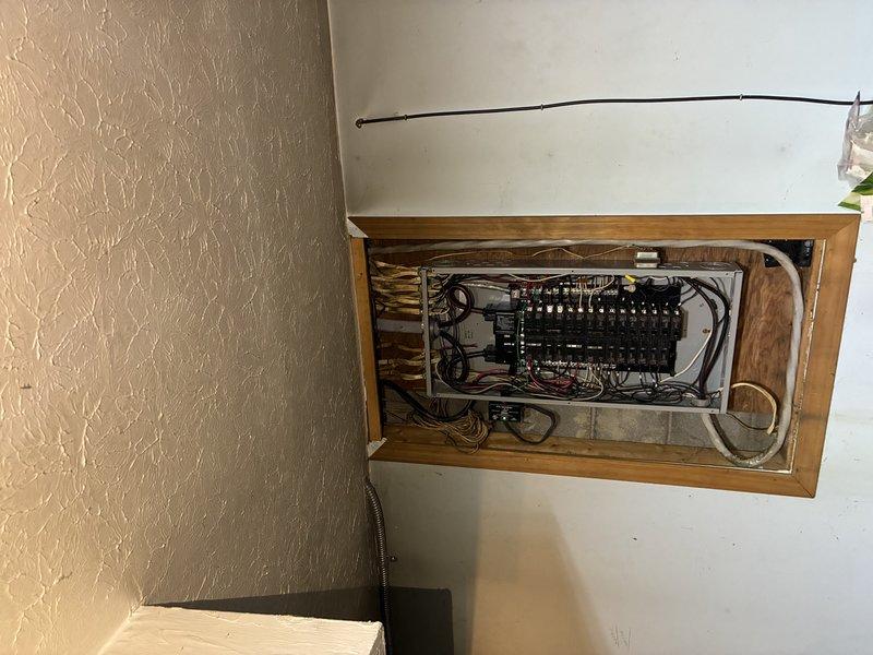 Conducted comprehensive assessment of existing electrical system to provide detailed quote for complete breaker box upgrade and whole-home rewiring project. Inspected current electrical panel installation housed in wooden cabinet enclosure, documenting multiple circuit breakers, wire routing configurations, and overall system condition. Evaluated attic and crawl space areas to assess existing wiring infrastructure, accessibility for new wire runs, and structural considerations for planned electrical upgrades. Photographed electrical panel interior showing current breaker arrangement, wire bundling, and connection points to establish baseline documentation for proposed scope of work. Assessment identified need for modern electrical service upgrade to meet current code requirements and household electrical demands.