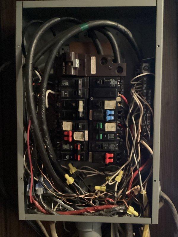 Responded to service call for partial power outage in 1981 double wide mobile home where occupant was relying on extension cords for power to half of the residence. Upon arrival, performed comprehensive inspection of main electrical distribution panel. Found multiple issues including disorganized wiring, improper wire connections with several wire nuts at bottom of panel, and evidence of overloaded circuits. Documented panel conditions with photographs showing aged breakers, bundled conductors entering from top and bottom, and mixed wire routing throughout enclosure. Panel exhibited signs of deterioration consistent with 45-year-old installation. Identified several circuit breakers in various states requiring attention, with colored indicators suggesting previous tripping or failures. Assessed overall electrical system integrity and determined extent of repairs needed to restore full power to affected areas of home. Provided detailed assessment and repair recommendations to restore saf