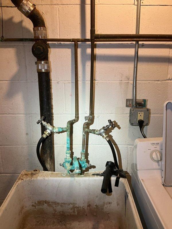 Responded to a plumbing repair request in a basement utility area where deteriorating cast iron piping had been temporarily patched with tape for several years. Removed and replaced the compromised cast iron section with new copper piping, addressing significant corrosion evident throughout the existing system. Installed a new faucet assembly over the utility sink adjacent to the washer area, replacing the corroded fixtures and brass shutoff valves. Repaired water-damaged wall sections surrounding the pipe penetrations where moisture infiltration had caused deterioration to the concrete and plaster surfaces. All connections were pressure-tested to ensure proper function and verify no leaks in the new installation.