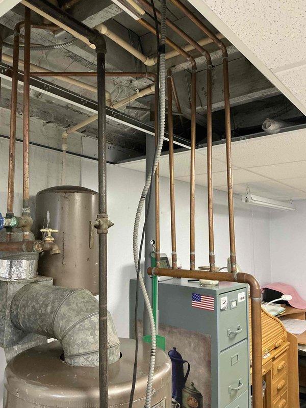 Conducted estimate for aging hydronic boiler system in basement utility area. System exhibits significant age-related deterioration with weathered components, corroded piping, and outdated infrastructure requiring complete replacement. Documented existing configuration including expansion tank, manifold with multiple zone valves, copper distribution piping, and primary heating unit for comprehensive replacement proposal.