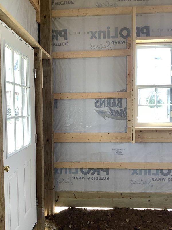Provided quote for electrical installation to supply power from main residence basement to detached outbuilding. Assessed exterior routing path along foundation and evaluated interior basement conditions where service originates. Coordinated site visit with plumbing contractor for concurrent work scheduling. Documented existing conditions including foundation access points, exterior siding penetration locations, and interior framing at outbuilding structure currently under construction with exposed studs and building wrap installed.