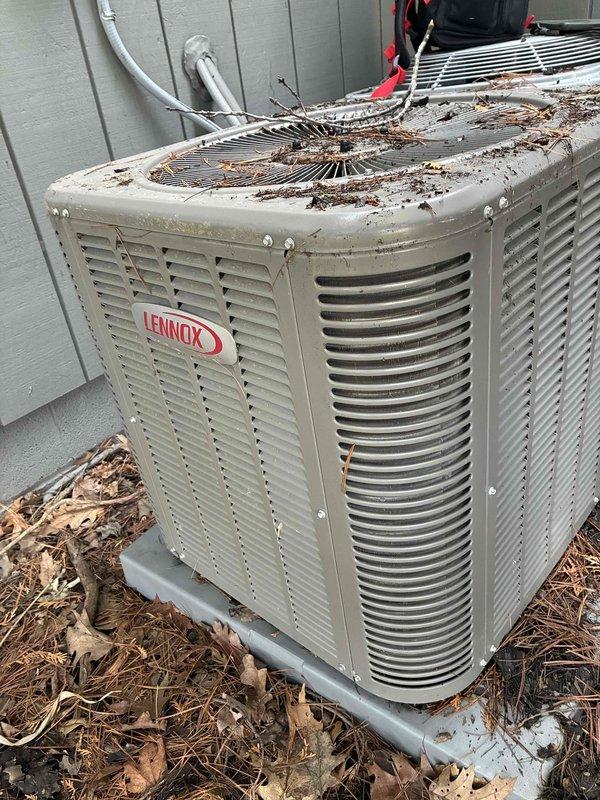 Completed routine MVP cooling maintenance visit on 7-year-old Lennox air conditioning system. Upon arrival, found outdoor condenser unit heavily covered with leaves, twigs, and organic debris on top surface and surrounding base area. Cleaned accumulated debris from condenser unit and inspected electrical service disconnect box mounted on exterior wall. Performed standard system inspection and maintenance procedures to ensure proper cooling operation for the season.