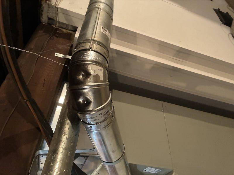 Replaced deteriorated flue pipe that was improperly secured with duct tape and actively leaking water with potential for dangerous gas leakage. Installed new B-type vent system with proper metallic ductwork sections and secure metal band connections to ensure safe venting of combustion gases. System now meets code requirements and operates safely without risk of water intrusion or exhaust gas spillage into living space.