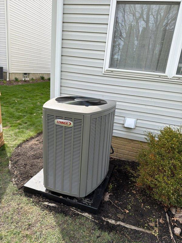 Completed full HVAC system installation including a new Lennox high-efficiency furnace in the basement utility area and matching Lennox outdoor condensing unit. The indoor installation features proper PVC venting configuration with dual vertical exhaust/intake pipes, integrated Aprilaire air quality equipment with control module and connecting conduit, and appropriate placement on the concrete floor with access to existing ductwork. The outdoor unit was positioned on a protective pad against the home's exterior with adequate clearance from the foundation and landscaping, ensuring proper airflow and serviceability. All components were installed per manufacturer specifications with proper electrical connections, refrigerant lines, and condensate drainage, resulting in a complete heating and cooling system ready for operation.