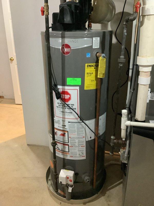 Responded to no hot water complaint at 27-year-old residence with existing tanked water heater system. Upon arrival, assessed Rheem residential water heater unit and associated plumbing infrastructure including expansion tank, copper supply lines, shut-off valves, and circulating pump assembly. Inspected all connections, electrical components, and safety labels for proper operation and code compliance. Documented existing installation showing water heater with integrated expansion tank, PVC venting system, copper water lines with red-handled ball valves, and recirculation pump mounted at top of unit. Verified all plumbing connections, valve operations, and system components. Photographed complete installation for service records showing proper configuration of hot and cold water lines, expansion tank mounting, electrical connections, and venting arrangement in basement mechanical room.