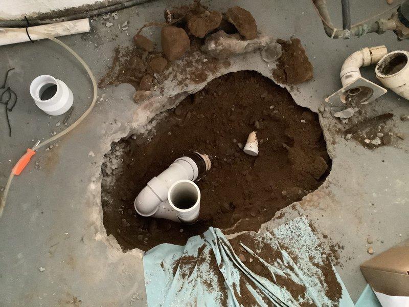 Removed existing defective floor drain and miscellaneous drainage system in basement by jackhammering concrete slab to expose underground drain lines. Installed new properly configured floor drain with PVC trap assembly. Rerouted water softener discharge line and existing 1 1/2" drain line to connect to new floor drain. Completed rough concrete pour to restore floor surface in excavated area. All drainage connections tested and verified operational.