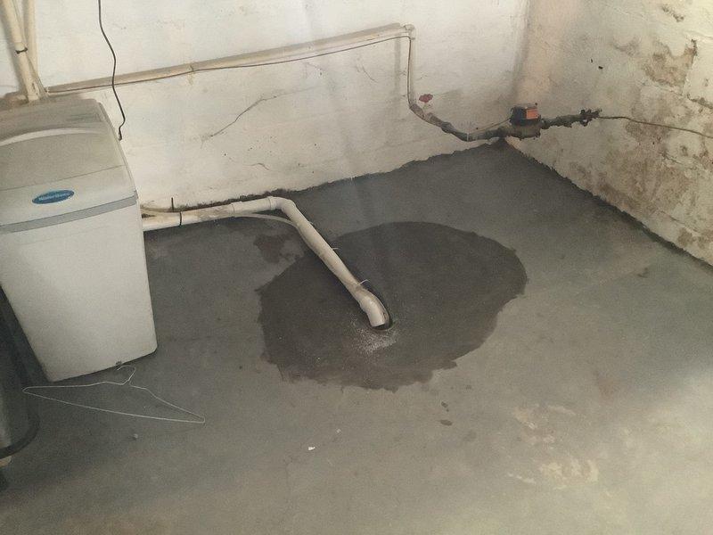 Removed existing defective floor drain and miscellaneous drainage system in basement by jackhammering concrete slab to expose underground drain lines. Installed new properly configured floor drain with PVC trap assembly. Rerouted water softener discharge line and existing 1 1/2" drain line to connect to new floor drain. Completed rough concrete pour to restore floor surface in excavated area. All drainage connections tested and verified operational.