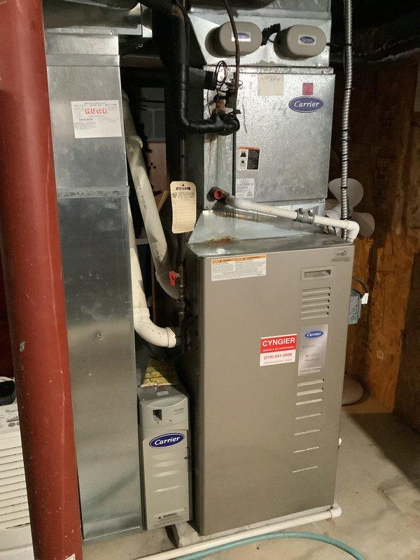 Conducted replacement estimate for approximately 18-year-old residential HVAC system in single-family home. Evaluated existing Carrier furnace and air handler installation in basement utility area, documented current equipment configuration including vertical stacking arrangement, PVC condensate drainage, and ductwork connections. Photographed system components and provided replacement recommendations based on equipment age and condition assessment.