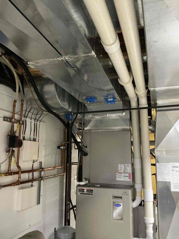 Conducted comprehensive site assessment for multi-zone HVAC system replacement including furnace, air conditioning, and heat pump equipment. Evaluated existing Carrier furnace/air handler installation, documented current ductwork configuration with metallic supply ducts and flexible connections, and assessed mechanical room infrastructure including electrical conduit routing, copper refrigerant line placement, and PVC condensate drainage. Inspected secondary heating system with associated copper piping and determined spatial requirements for new equipment installation in basement mechanical room with consideration for existing boiler system and available clearances.