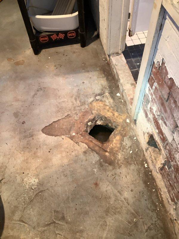 Responded to main drain line stoppage at century-old single-family residence requiring cleanout from house to street connection. Upon arrival, discovered significant deterioration in basement utility area including damaged concrete floor with large opening near wall intersection, extensive moisture staining, and compromised wall surfaces indicating long-term water infiltration issues. Successfully cleared main sewer line obstruction using professional drain cleaning equipment. Documented existing conditions including water heater installation, overhead plumbing infrastructure, and basement structural concerns for homeowner records and potential future remediation needs.