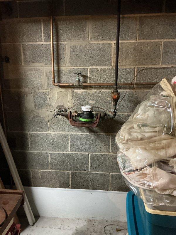 Responded to service call for malfunctioning pressure regulator valve and thermal expansion tank in 66-year-old residential property. Upon arrival, inspected existing plumbing assembly mounted on basement utility wall, noting significant age-related corrosion and oxidation on copper piping and valve components. Water meter assembly and associated gate valves showed weathering consistent with original installation. Evaluated pressure regulation system and thermal expansion tank functionality, documented existing conditions through photography for service records. Assessed copper pipe loop configuration and connection points to determine extent of component degradation and system performance issues affecting household water pressure regulation.