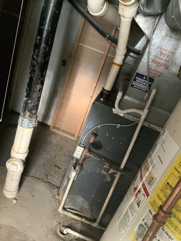 Completed HVAC estimate for furnace replacement at residential property. Evaluated existing 19-year-old furnace system, assessed current equipment condition showing significant age-related wear and dust accumulation, documented existing PVC condensate drain configuration and venting infrastructure, and photographed mechanical room layout including furnace unit, electrical connections, and associated plumbing components to provide comprehensive replacement quote.