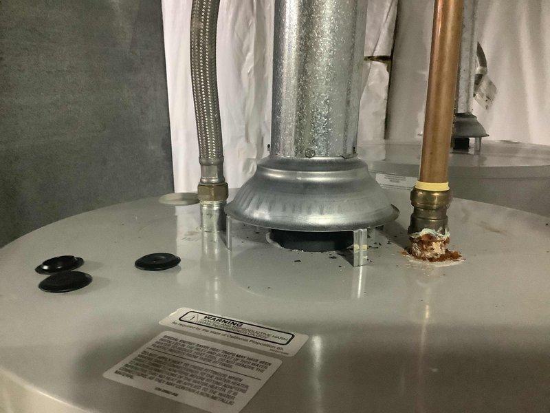 Responded to service call for water heater inspection following HVAC technician's referral. Upon arrival, performed comprehensive evaluation of Bradford White 50-gallon natural gas water heater, model RG450T6N with 40,000 BTU/hr input rating. Documented equipment condition through photographic inspection, noting significant corrosion buildup at copper pipe brass connector on hot water outlet. Observed condensation present on galvanized vent pipe and confirmed all manufacturer specification labels and safety warnings intact and legible. Verified proper clearances for closet installation per ANSI standards. Equipment operational at time of inspection with all connections and fittings accessible for maintenance.