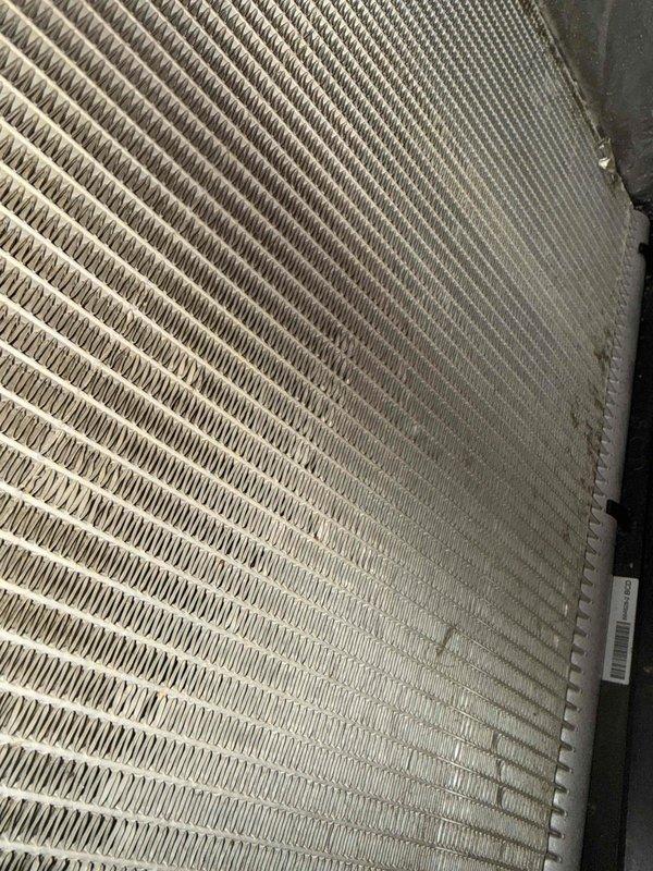 Completed MVP cooling visit and preventive maintenance inspection. Documented electrical disconnect panel showing operational fuse assembly with visible age-related corrosion on internal components and hardware, though all connections remain secure. Inspected condenser coil fins which are in clean condition with proper airflow clearance and no significant debris accumulation or damage present.