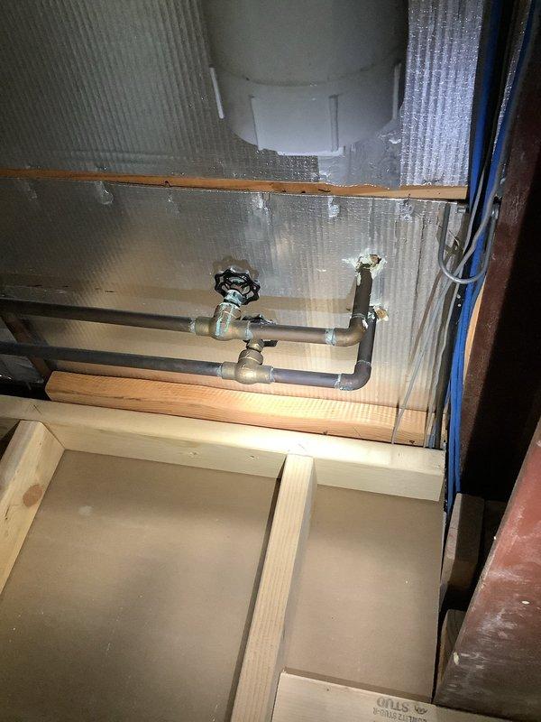 Responded to a water leak originating from second-floor bathroom plumbing that was causing damage to the first-floor ceiling. Upon inspection, accessed the affected area through ceiling access point and examined exposed plumbing components, including PVC drainage lines, galvanized steel pipe assembly with shut-off valve, and connections mounted against foil-backed insulation. Documented visible water staining and discoloration on first-floor ceiling surfaces indicating active moisture infiltration from the bathroom above.