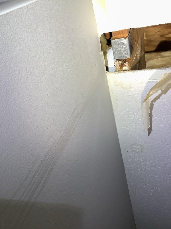 Responded to a water leak originating from second-floor bathroom plumbing that was causing damage to the first-floor ceiling. Upon inspection, accessed the affected area through ceiling access point and examined exposed plumbing components, including PVC drainage lines, galvanized steel pipe assembly with shut-off valve, and connections mounted against foil-backed insulation. Documented visible water staining and discoloration on first-floor ceiling surfaces indicating active moisture infiltration from the bathroom above.