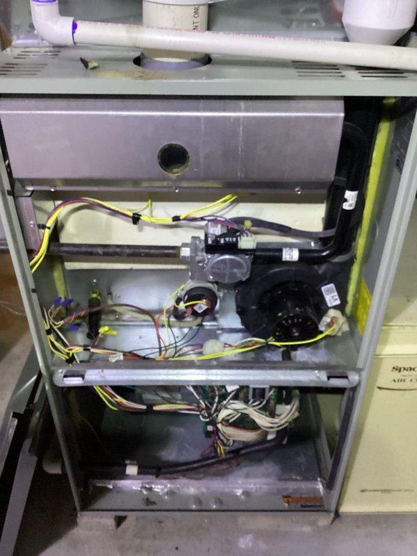 Responded to service call for odor in furnace room and thermostat beeping issue. Performed thorough inspection of furnace unit and associated components, including visual examination of internal components, heat exchanger, blower assembly, electrical connections, and condensate drainage system. Inspected water heater and gas piping connections in mechanical room for potential gas odor source. Documented equipment condition with photographs showing wiring harnesses, control modules, and safety systems. Verified all electrical connections secure and assessed overall system operation for early 1990s residential installation.