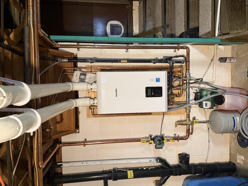 # HVAC Install - Boiler

Completed installation of a combi boiler system with buffer tank integration over a two-day period. The primary unit installed was an AXTON DMF-150 model with digital display and control interface, mounted on a tiled wall in the mechanical room. Established complete copper piping network connecting the boiler to existing plumbing infrastructure, including proper valve placement for system isolation and maintenance access.

Integrated a blue expansion vessel to maintain proper system pressure and accommodate thermal expansion. Connected the buffer tank (green cylindrical unit) to the combi boiler system using brass fittings and appropriate piping configurations to ensure optimal heat distribution and system efficiency. The buffer tank features digital temperature monitoring with LED display showing real-time system readings.

Installed electrical components including power transformer with indicator light for system status monitoring. Routed and secured all elec