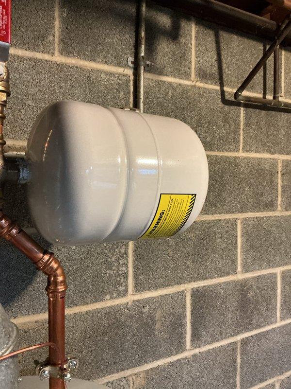 Replaced failed pressure reducing valve (PRV) with new unit and installed ball valve for improved system isolation and maintenance access. Removed old expansion tank and installed new replacement tank to maintain proper system pressure control and prevent thermal expansion damage to plumbing system. All copper connections were properly fitted and secured, with components mounted to concrete block wall using appropriate brackets and supports.