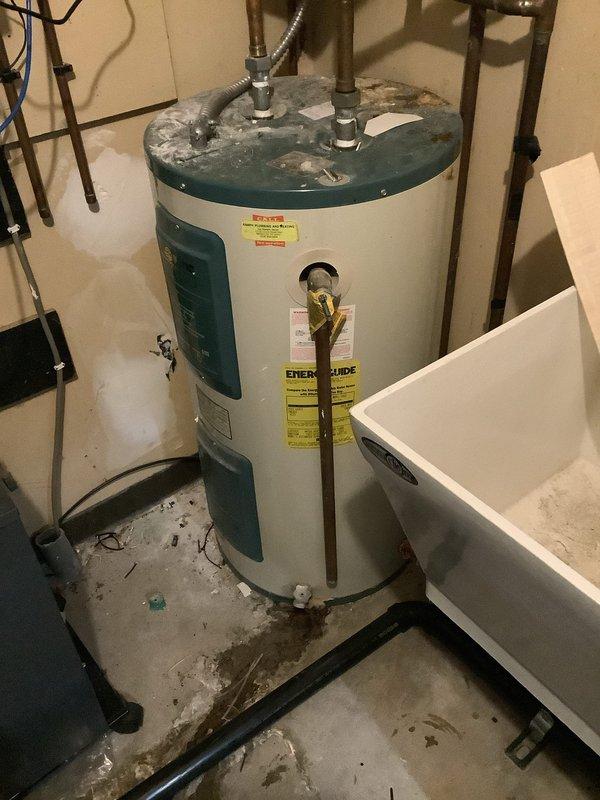 Responded to service call for leaking residential water heater in utility closet. Upon inspection, found active leak from deteriorated tank with visible corrosion and mineral deposits on top surface and connections. Water heater showed signs of age-related failure with compromised tank integrity. Documented existing plumbing configuration including copper supply lines, expansion tank installation, shut-off valves, and flexible connectors. Assessed water damage to surrounding concrete floor and utility closet area. Provided estimate for complete water heater replacement due to tank failure. Also provided separate estimate for removal of existing utility sink from same closet per customer request.