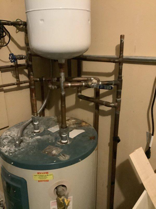 Responded to service call for leaking residential water heater in utility closet. Upon inspection, found active leak from deteriorated tank with visible corrosion and mineral deposits on top surface and connections. Water heater showed signs of age-related failure with compromised tank integrity. Documented existing plumbing configuration including copper supply lines, expansion tank installation, shut-off valves, and flexible connectors. Assessed water damage to surrounding concrete floor and utility closet area. Provided estimate for complete water heater replacement due to tank failure. Also provided separate estimate for removal of existing utility sink from same closet per customer request.