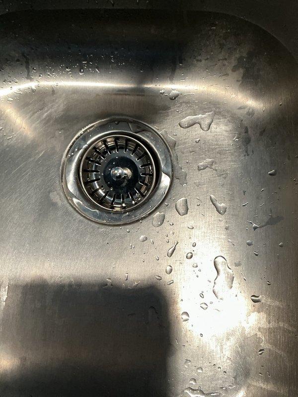 Successfully installed customer-supplied kitchen faucet with single-handle design and brushed stainless steel finish on granite countertop. Replaced basket strainer assembly on left basin of double-bowl stainless steel sink, ensuring proper seal and drainage function. Both installations completed using customer-provided fixtures and materials.